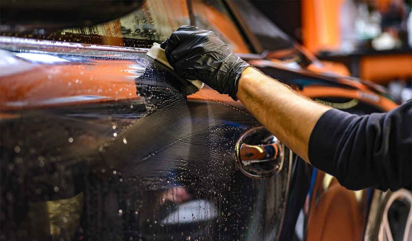 Technician foam washing a black car